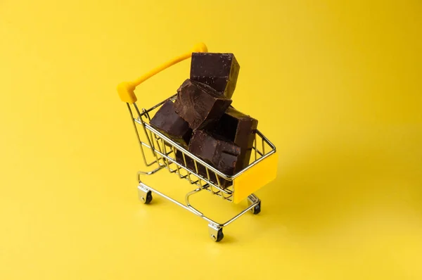Bitar av mörk choklad i en livsmedelsvagn isolat på gul bakgrund närbild, kopiera utrymme — Stockfoto