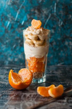 Sağlıklı yaşam tarzı, düzgün beslenme ve sağlıklı kahvaltı kavramı. Muzlu yoğurt, yulaf ezmesi ve mandalina, eski bir kaşıkla birlikte.