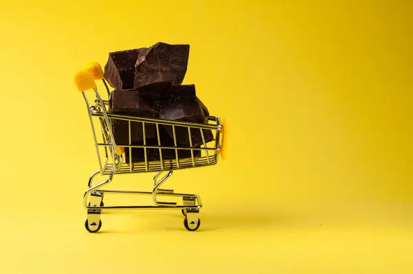 Trozos Chocolate Negro Carro Compra Aíslan Sobre Fondo Amarillo Cerca — Foto de Stock