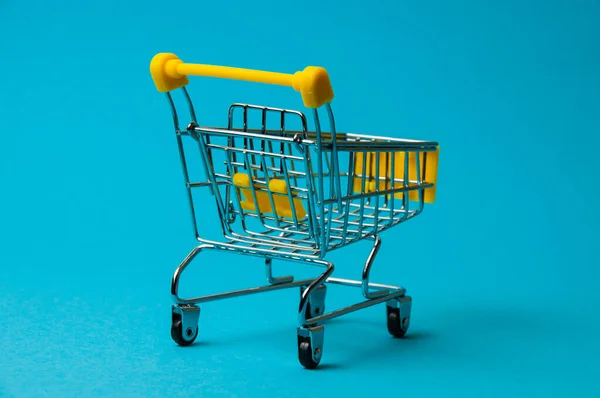 Trolley for shopping on blue background. Supermarket food price concept, holiday discounts