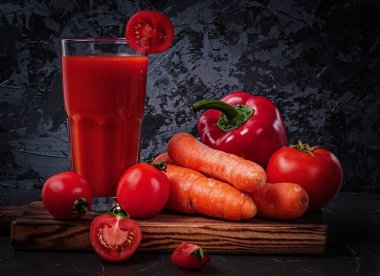 Bardaktaki sebze suyu ve kesme tahtasındaki sebze suyu: havuç, biber ve domates.