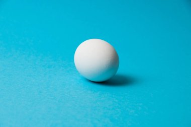 Mavi arka planda bir beyaz yumurta. Kalori içeriği, yaşam, sağlıklı beslenme, Paskalya