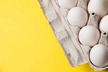 Sarı arka planda bir tepside tavuk yumurtası, boşluğu kopyala