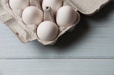 Hafif ahşap zemin üzerinde tepside beyaz tavuk yumurtaları, kopyalama alanı