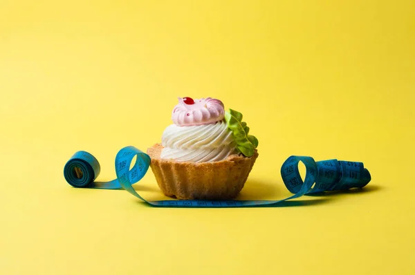 Cake and centimeter on yellow background. Calorie and diet concept