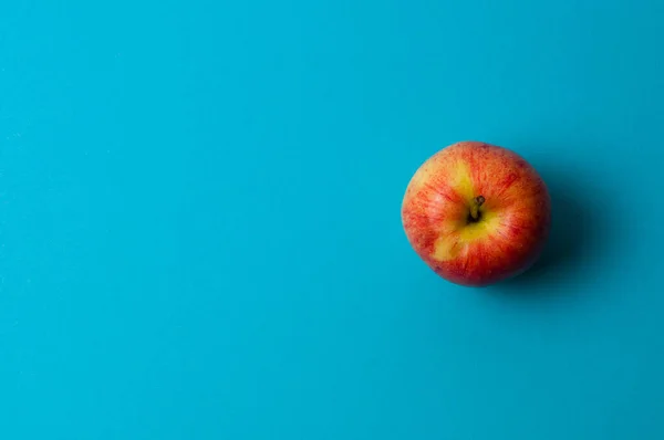 Apple on blue background. Healthy eating, calorie count and weight loss concept