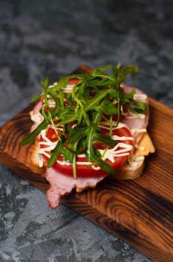 Jambonlu, balyklı, roka peynirli, domatesli ve mayonezli iştah açıcı sandviç.