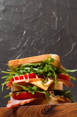 Jambonlu, balyklı, roka, peynirli, domatesli ve mayonezli büyük lezzetli sandviç. Köy usulü, arka planda gri bir görünüm var. Boşluğu kopyala.