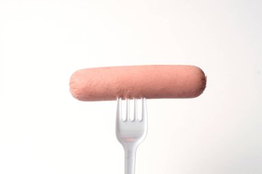 Beyaz arka planda plastik çatallı çiğ sosis.