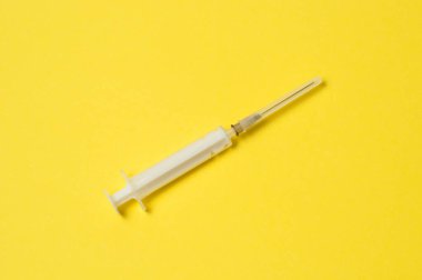 Sarı arka planda tıbbi şırınga var.