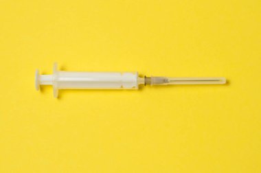 Sarı arka planda tıbbi şırınga var.