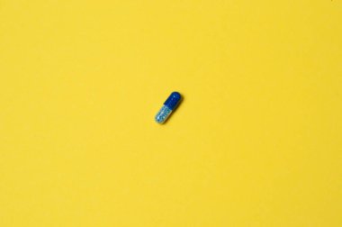 Sarı zemin üzerinde mavi hap, izole, metin için yer ile