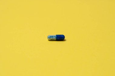 Sarı zemin üzerinde mavi hap, izole, metin için yer ile