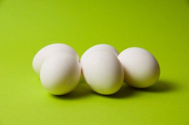 Parlak yeşil arka planda birkaç tavuk yumurtası, kopyalama alanı