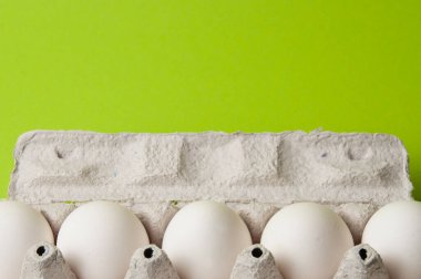 Neon yeşil arka planda açık bir tepside yumurtalar