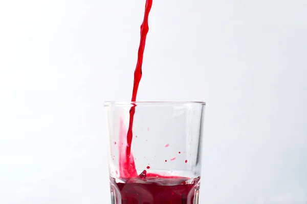 Grape and pomegranate juice pouring into glass, isolate on a white background