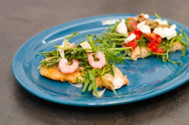 Karides, roka, domates, peynir ve sos, yakın plan, gri arka plan, yüksek İtalyan mutfağı.