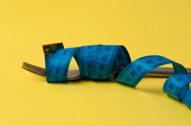 Sarı arka planda çatal ve santimetre. Konsept diyet, sağlıklı beslenme ve kilo kaybı