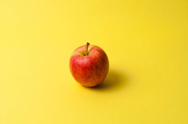 Sarı arka planda bir kırmızı elma. Fikir, kilo kaybı ve uygun beslenme kavramı