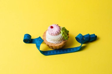 Sarı arka planda kek ve santimetre. Kalori ve diyet konsepti