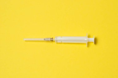 Sarı arka planda tıbbi şırınga var.