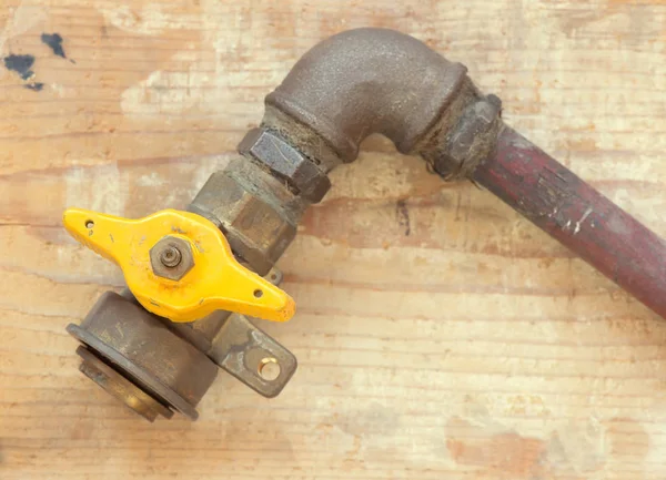 Old gas with yellow ball valve on wooden background