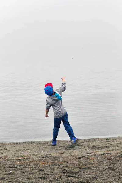 Αγόρι ρίχνει ροκ στο νερό. — Φωτογραφία Αρχείου