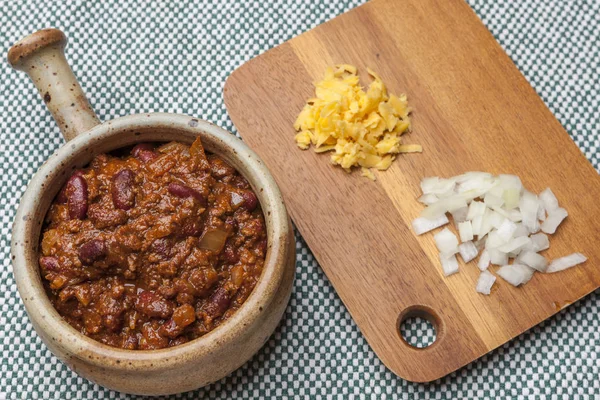 Kom van chili met kaas en uien aan kant. — Stockfoto