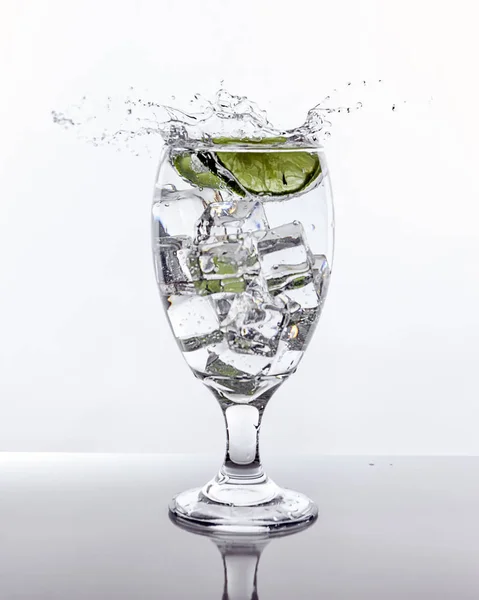 Lime splashes into glass of water. — Stock Photo, Image