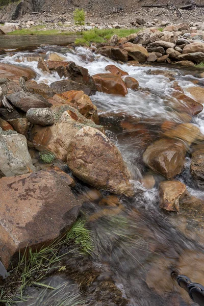 El agua fluye sobre rocas y hierba . — Foto de Stock