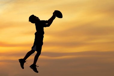 Top oynarken çocuk silüeti.