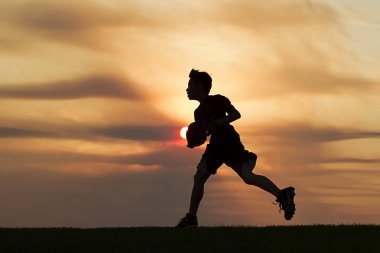 Siluet günbatımında çalışan çocuk.