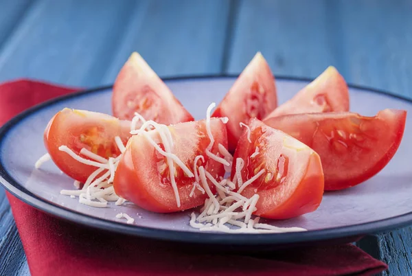Geraspte kaas op tomaat wiggen. — Stockfoto