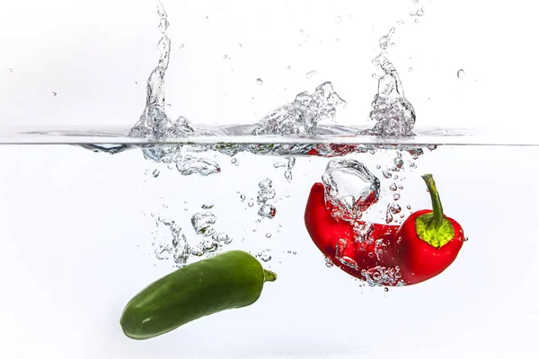 Röd och grön peppar tappade i vatten. — Stockfoto
