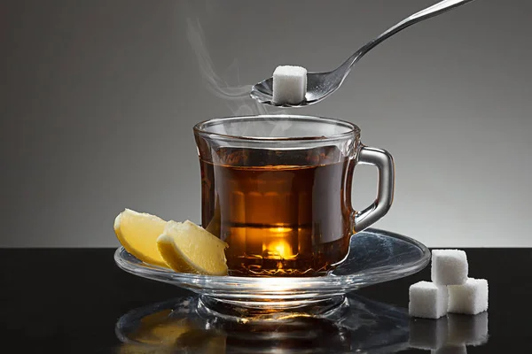 Mettre du sucre cube dans le thé chaud . — Photo