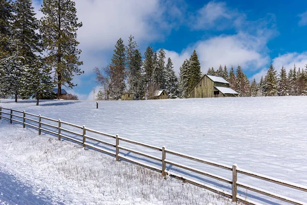 Zaun um verschneites Feld und Scheune. — Stockfoto