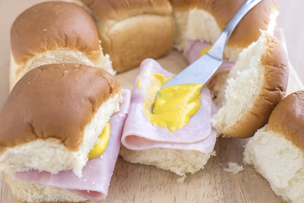 Putting mustard on a ham on roll sandwich. — Stock Photo, Image