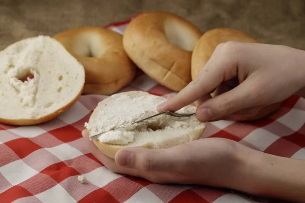 Putting cream cheese on a bagel. — Stock Photo, Image