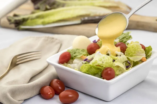 Gieten dressing op een salade. — Stockfoto