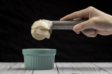 Vanilyalı dondurmayı kaseye koymak. Bir kepçe vanilyalı dondurma metal bir dondurmanın içinde.