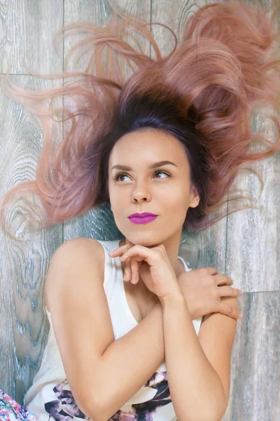 Jonge vrouw met roze lippen liggend op houten parket — Stockfoto