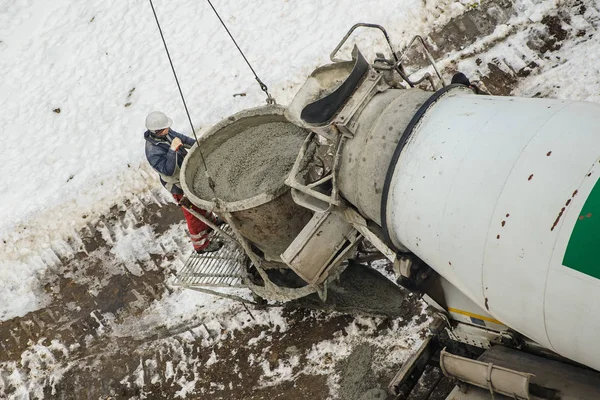 Concrete mixer truck pouring liquid concrete into the tower cran