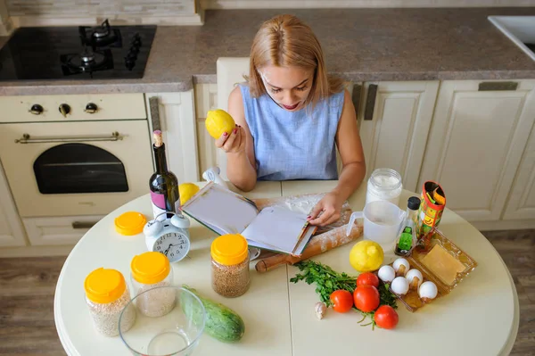 housewife reading cooking book in her kitchen top view