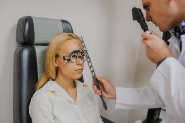 Genç güzel doktor/uzman/gözlükçü bir ophthalm içinde göz