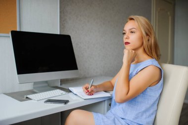 Mavi elbiseli bir pc üzerinde çalışan ciddi genç kadın