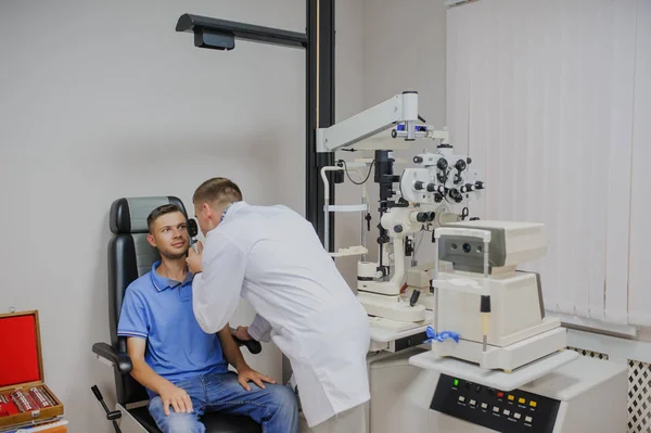 Jovem médico bonito / oftalmologista / optometrista em um oftalmo — Fotografia de Stock