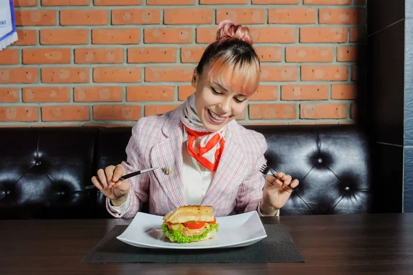 A young girl with pink hair eats a sandwich in a vintage cafe — Stock Photo, Image