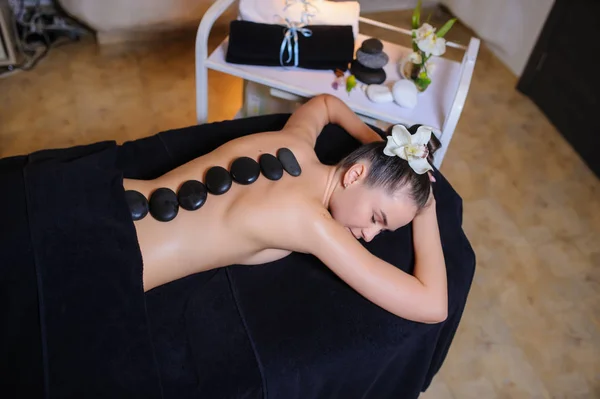 Terapia de pedra em um cliente feminino em beleza spa vista lateral — Fotografia de Stock