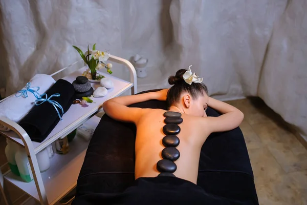 Terapia de piedra en una clienta femenina en el spa de belleza vista lateral — Foto de Stock