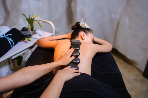 Terapia de piedra en una clienta femenina en el spa de belleza vista lateral — Foto de Stock